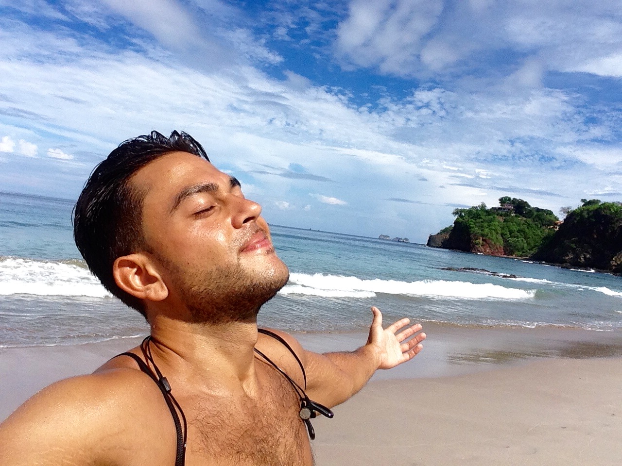 Sean Ali standing on a beach with arms open during a manifestation and freedom season