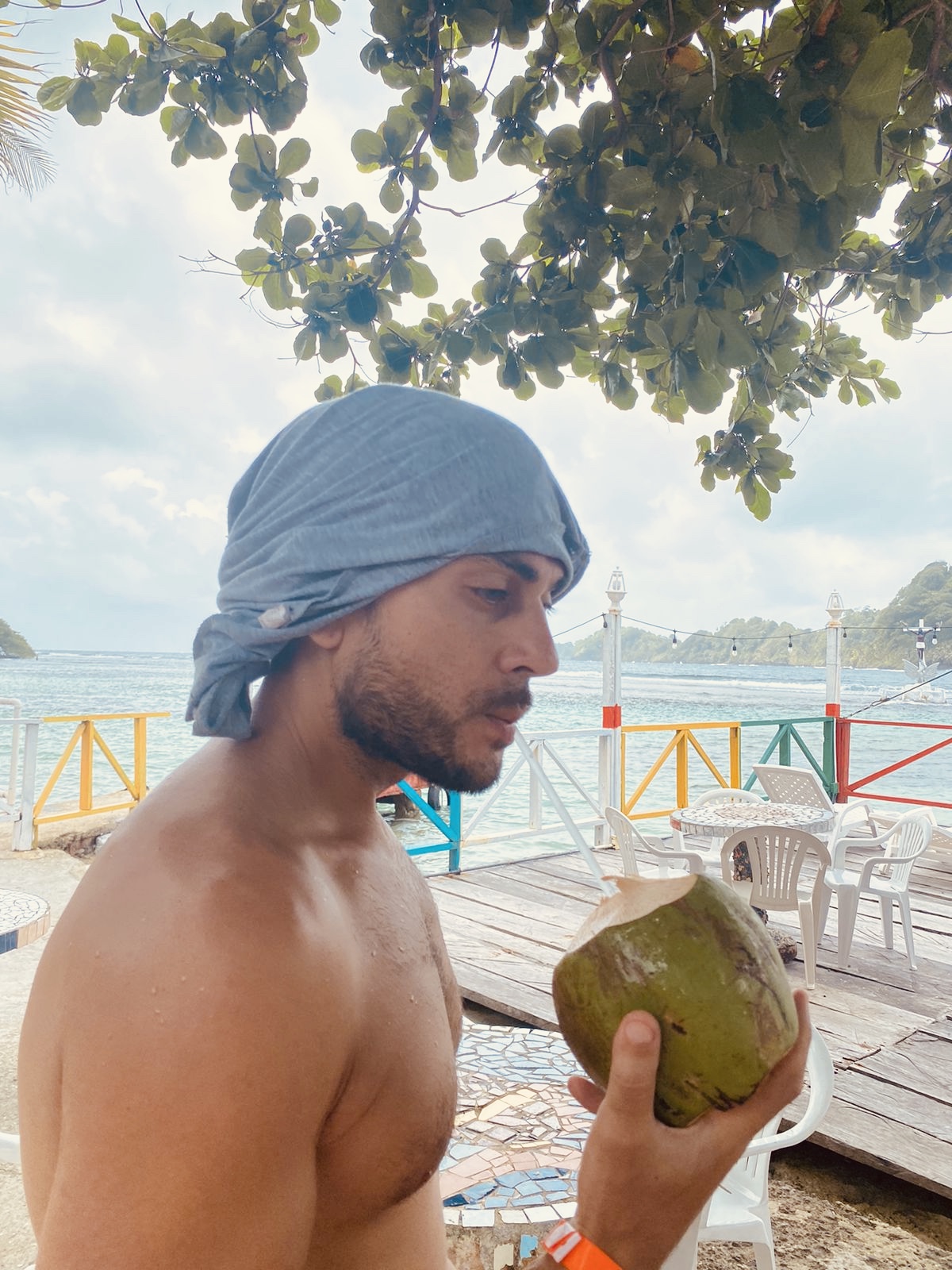 Sean Ali holding a coconut on a beach during a manifestation and lifestyle season